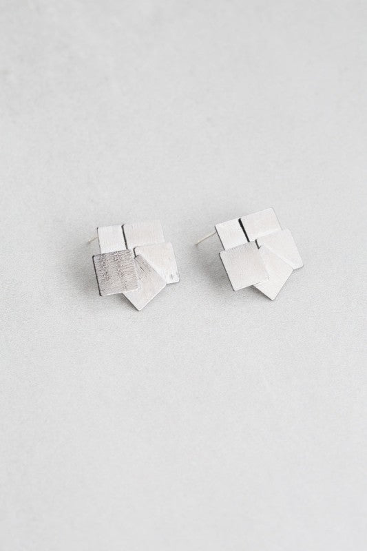Top view of overlapping gunmetal square stud earrings.