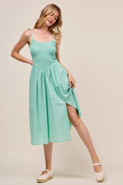 Front view of the Berkley Smocked Midi Dress in sage, showcasing the smocked bodice, adjustable spaghetti straps, and relaxed midi-length skirt.