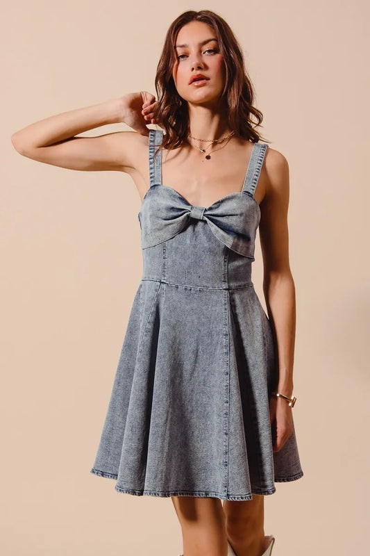 Front view of model wearing the Cassidy Denim Mini Dress showcasing the bow ribbon detail and flared silhouette.