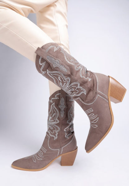 Model wearing taupe rhinestone cowboy boots styled with cream pants