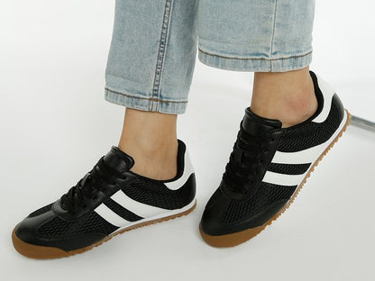 Side angled view of model wearing black Blaster sneakers with white stripes, featuring mesh upper and lug sole – casual sporty style by Rag Company