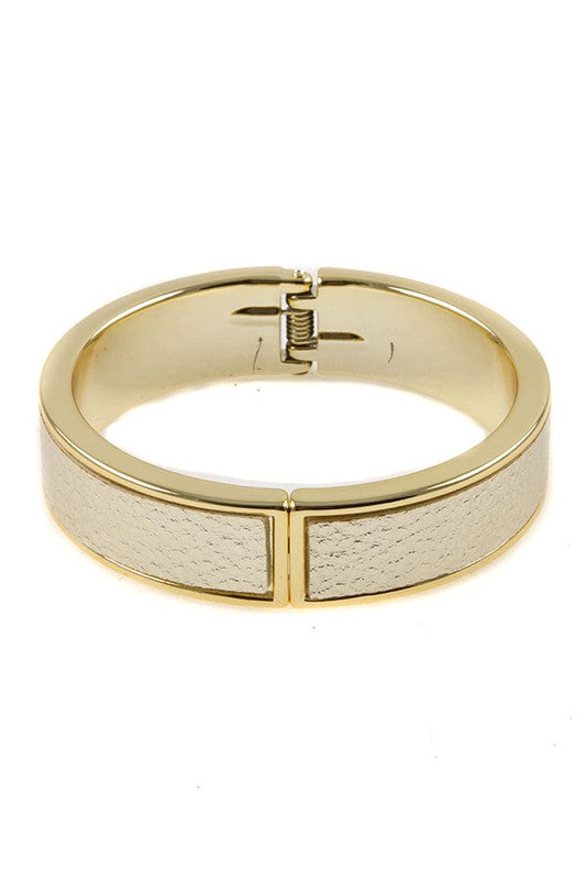 Gold bangle bracelet with cream leather insert and hinged closure, shown front view.