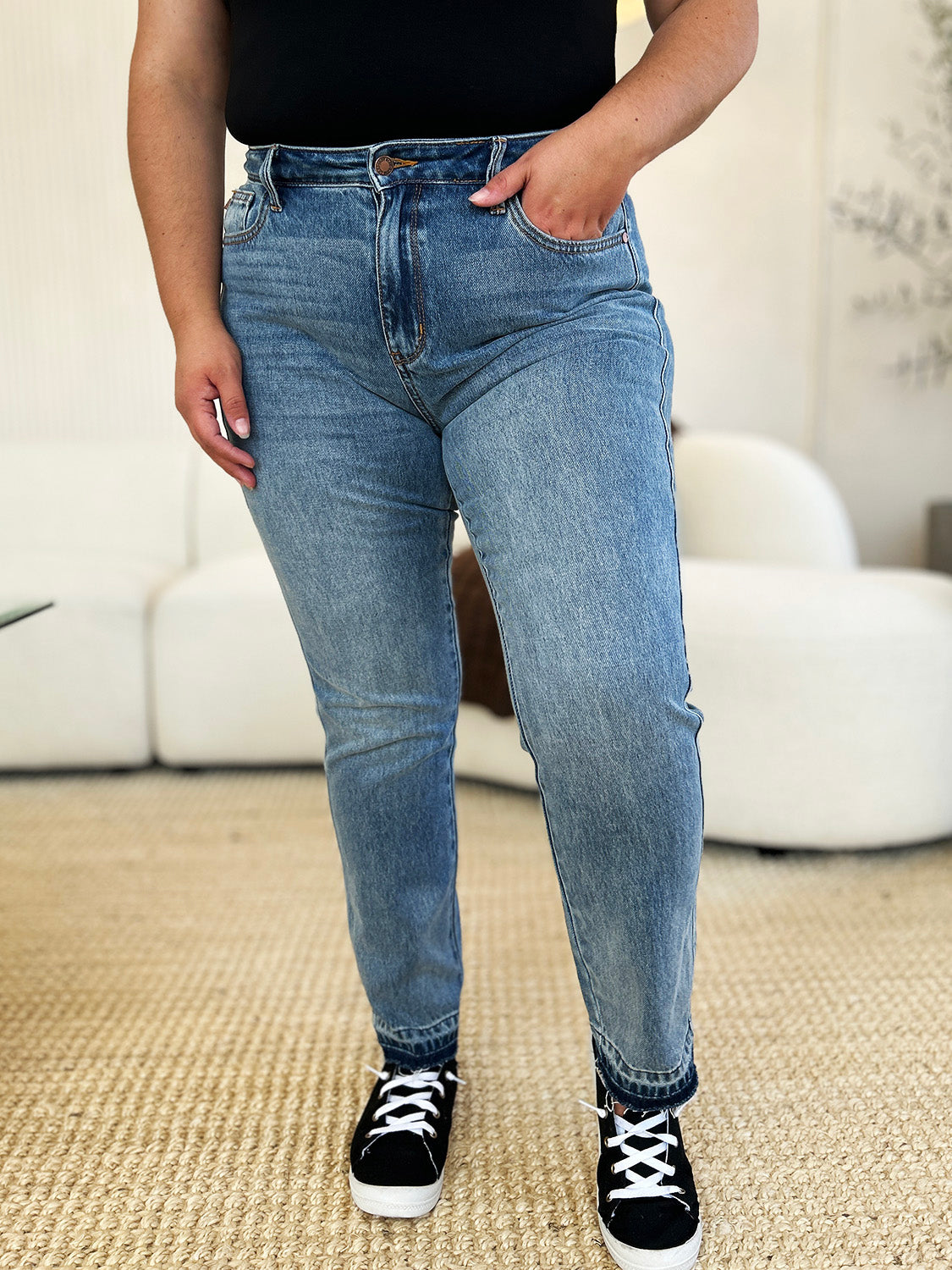 Medium wash mid-rise jeans with rigid fabric and released hem detail, featuring a relaxed fit and moderate stretch by Judy Blue.