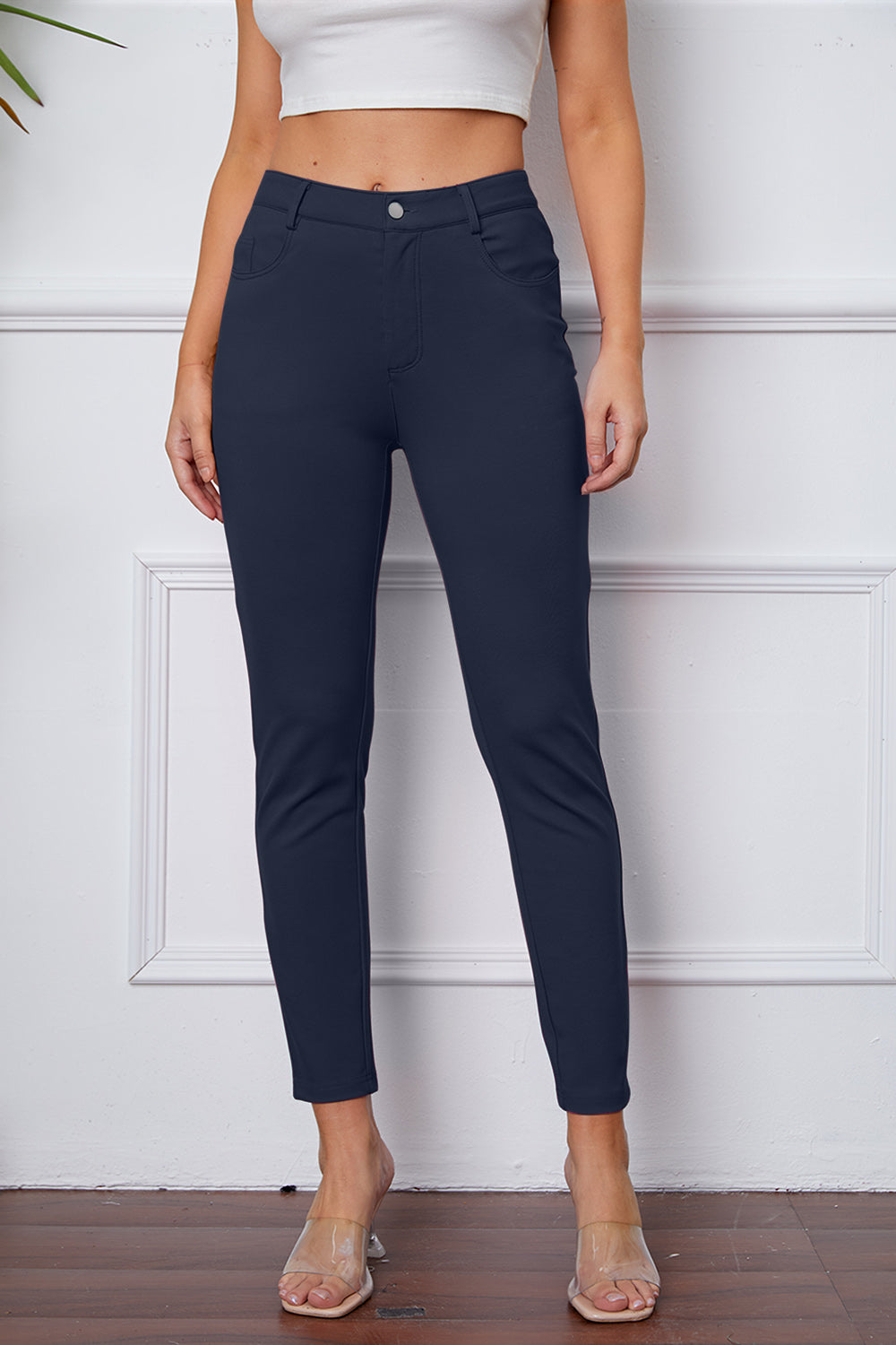 Navy stretchy high-waisted pants feature pockets, a zip fly, and belt loops. 