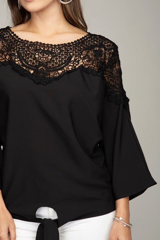 Stylish black blouse with a round neck, delicate lace details, and three-quarter sleeves.