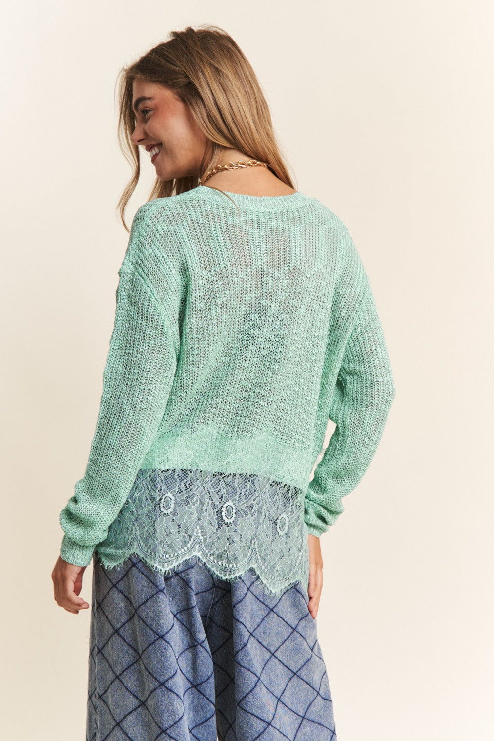 Women's sage sweater with lace detail, round neckline, long sleeves, and slightly stretchy fabric.