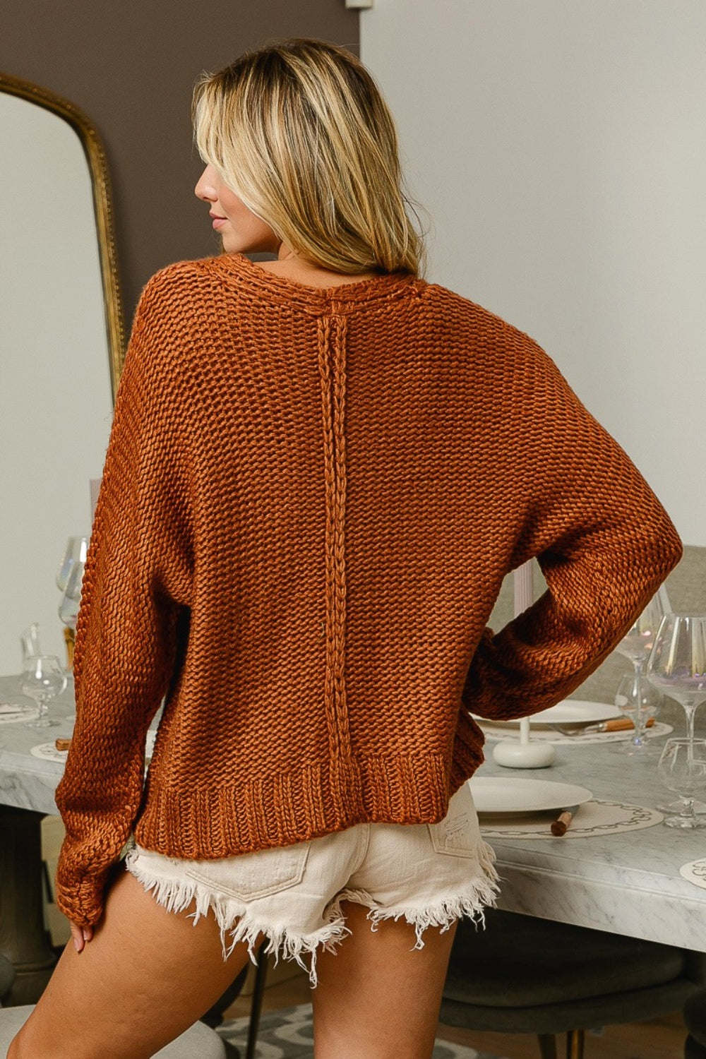 Cinnamon colored cable-knit sweater with long sleeves and a V-neck neckline.