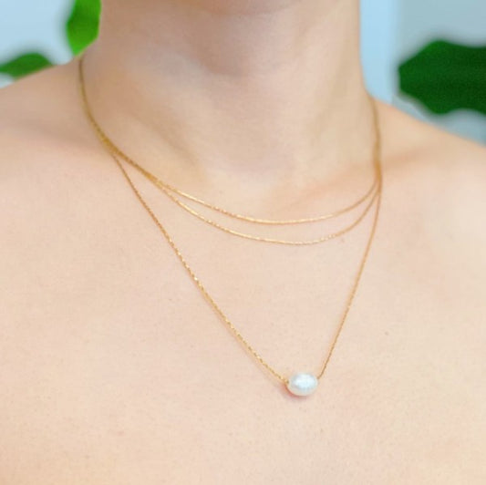 Woman wearing layered freshwater pearl pendant necklace close-up