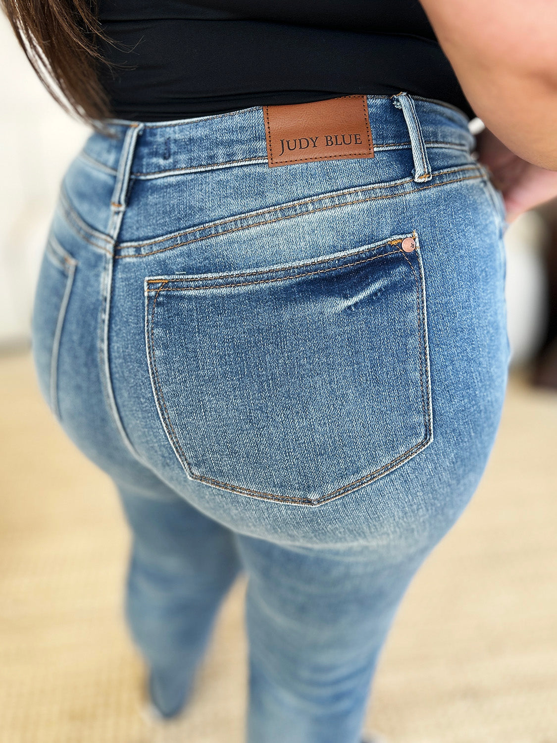 Medium wash mid-rise jeans with rigid fabric and released hem detail, featuring a relaxed fit and moderate stretch by Judy Blue.