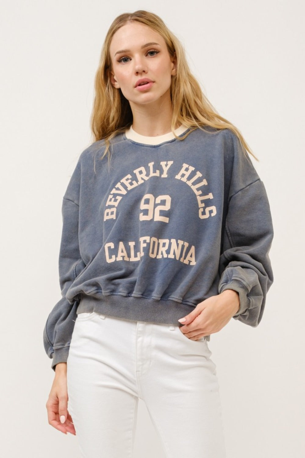 Cropped sweatshirt in stone color with "Beverly Hills 92 California" graphic text and contrast detailing.