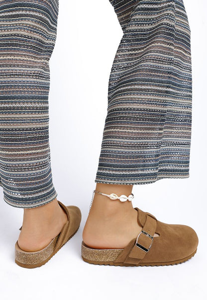 Model wearing Tan Ratiha Mules showing side and back view with tread sole and flat heel.
