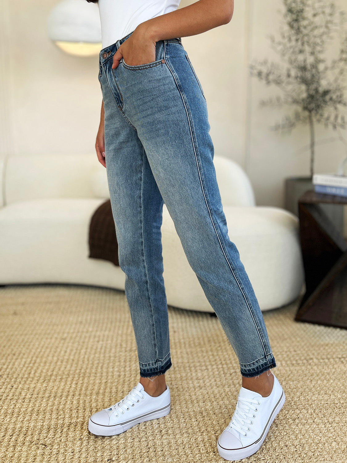 Medium wash mid-rise jeans with rigid fabric and released hem detail, featuring a relaxed fit and moderate stretch by Judy Blue.