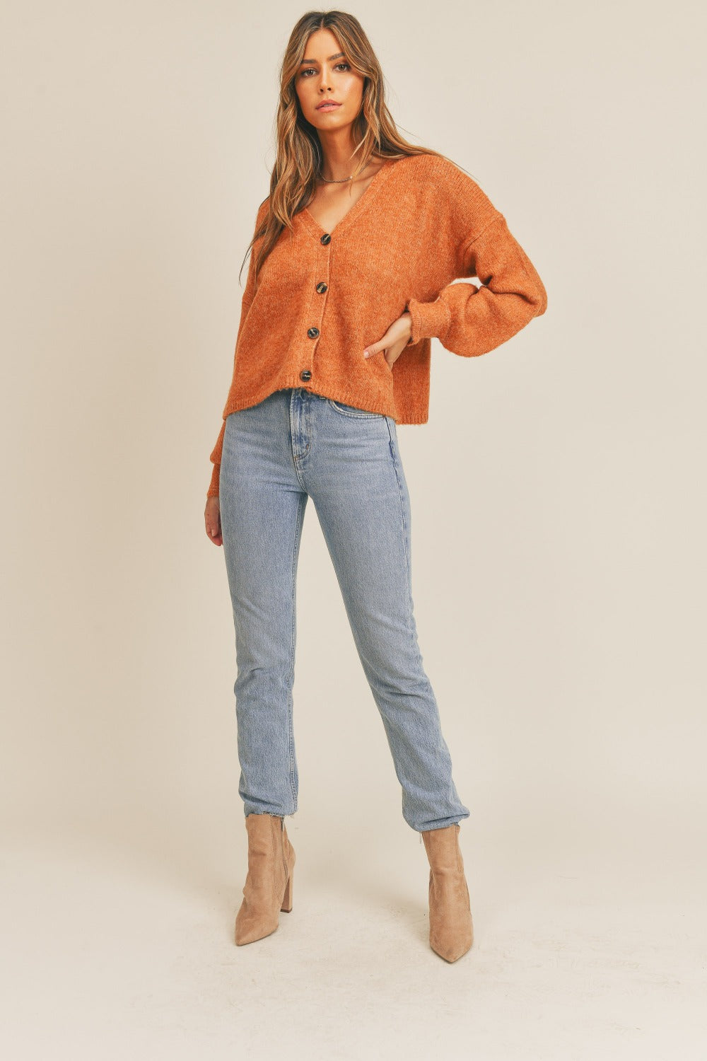 Women's rust colored cardigan with a V-neckline, long sleeves, button-down closure, and a relaxed fit.