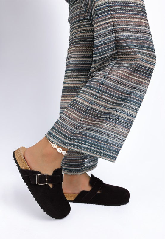 Model wearing Black Ratiha Mules showing inside and outside side views with cushioned insole and flat heel.
