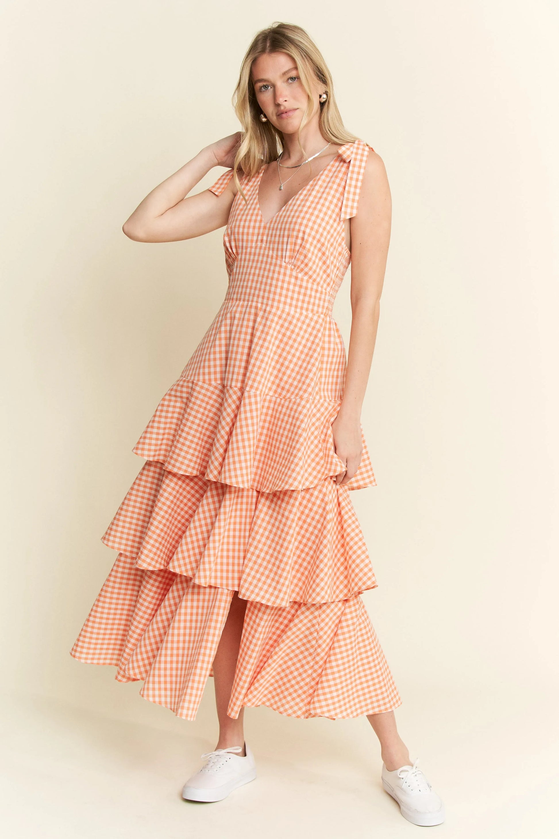 Full body front view of model wearing Alice Gingham Tiered Midi Dress by Jade by Jane, styled with sneakers and featuring tied bow sleeves and V-neckline.