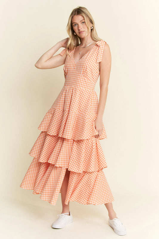 Full body front view of model wearing Alice Gingham Tiered Midi Dress by Jade by Jane, styled with sneakers and featuring tied bow sleeves and V-neckline.