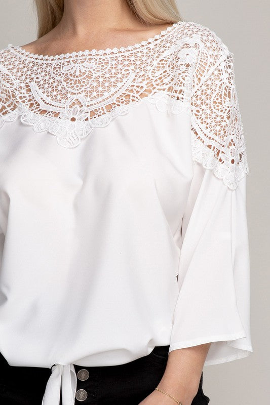 Stylish white blouse with a round neck, delicate lace details, and three-quarter sleeves.