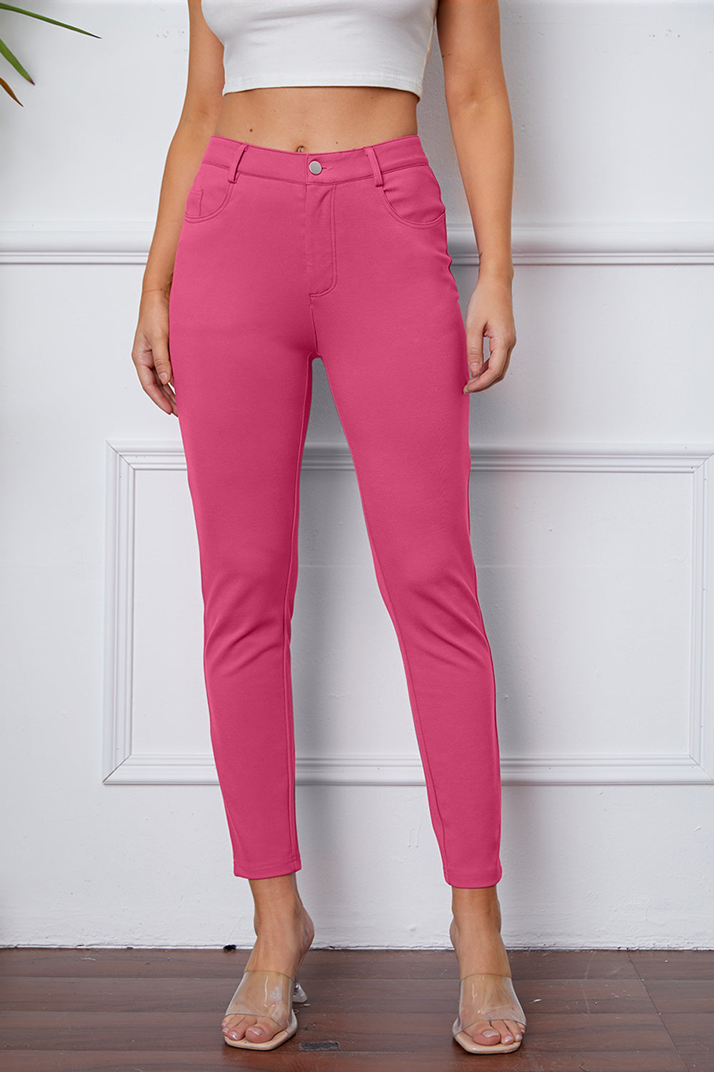 Fuchsia pink stretchy high-waisted pants feature pockets, a zip fly, and belt loops. 