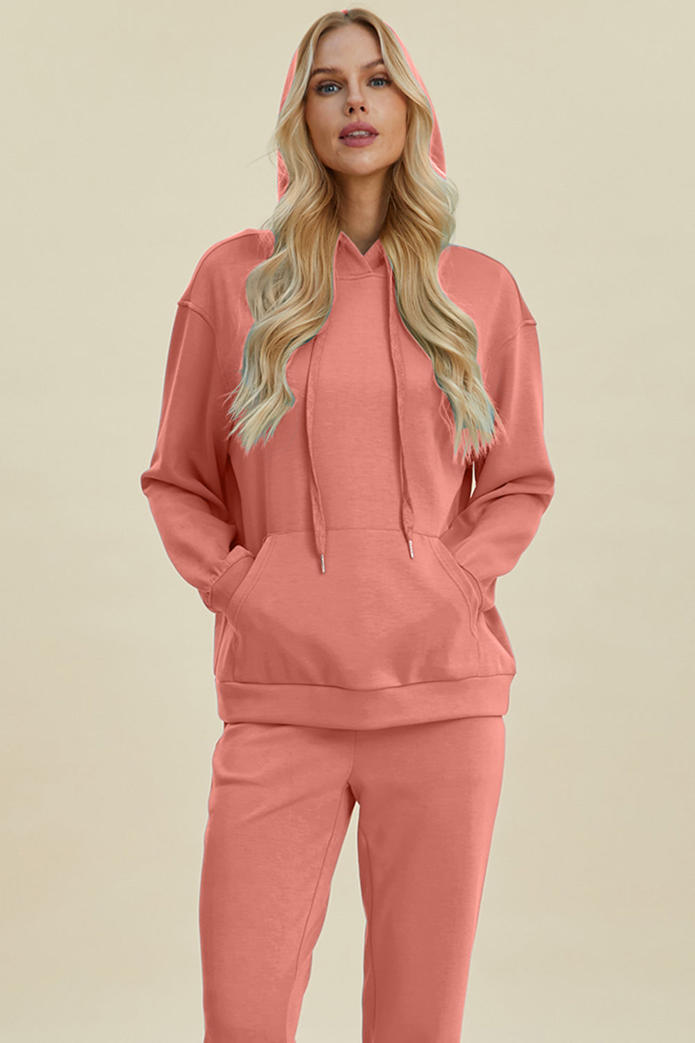 Coral long sleeve hoodie with kangaroo pocket, featuring a drawstring hood andrelaxed fit.