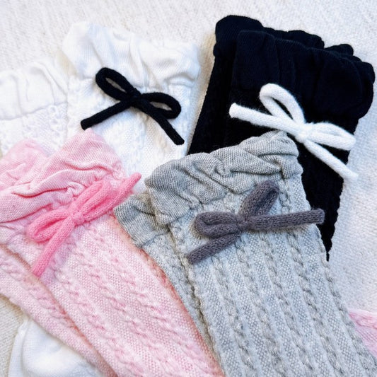 Flat lay of Adorable Yarn Bow Socks in pink, grey, black, and white showing bow detail.