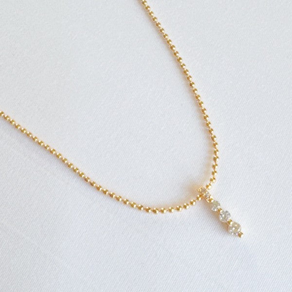 Flat lay of Three Sparkles Necklace with gold chain and three crystal drops