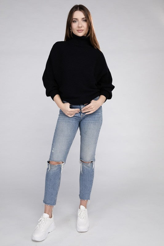 Black loose fitting turtleneck sweater, with ribbed knit texture, dolman sleeves, and raw hem detailing.