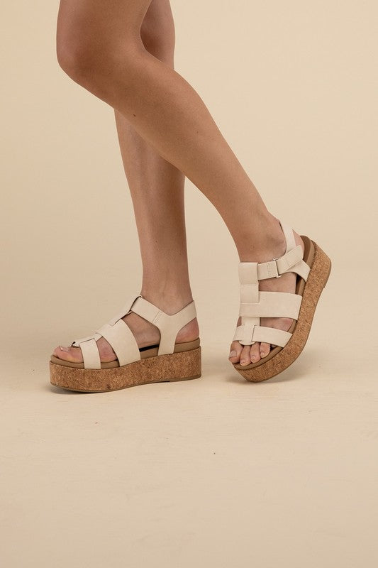 Beige platform wedge sandals with a buckle closure and 1.5" heel.