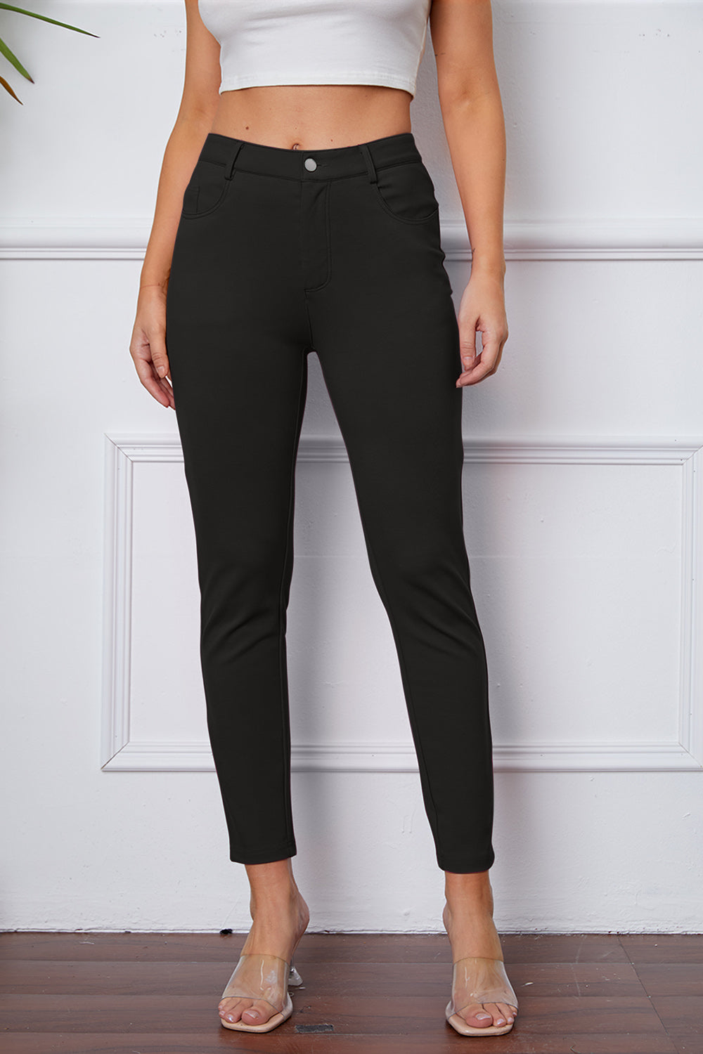 Black stretchy high-waisted pants feature pockets, a zip fly, and belt loops. 