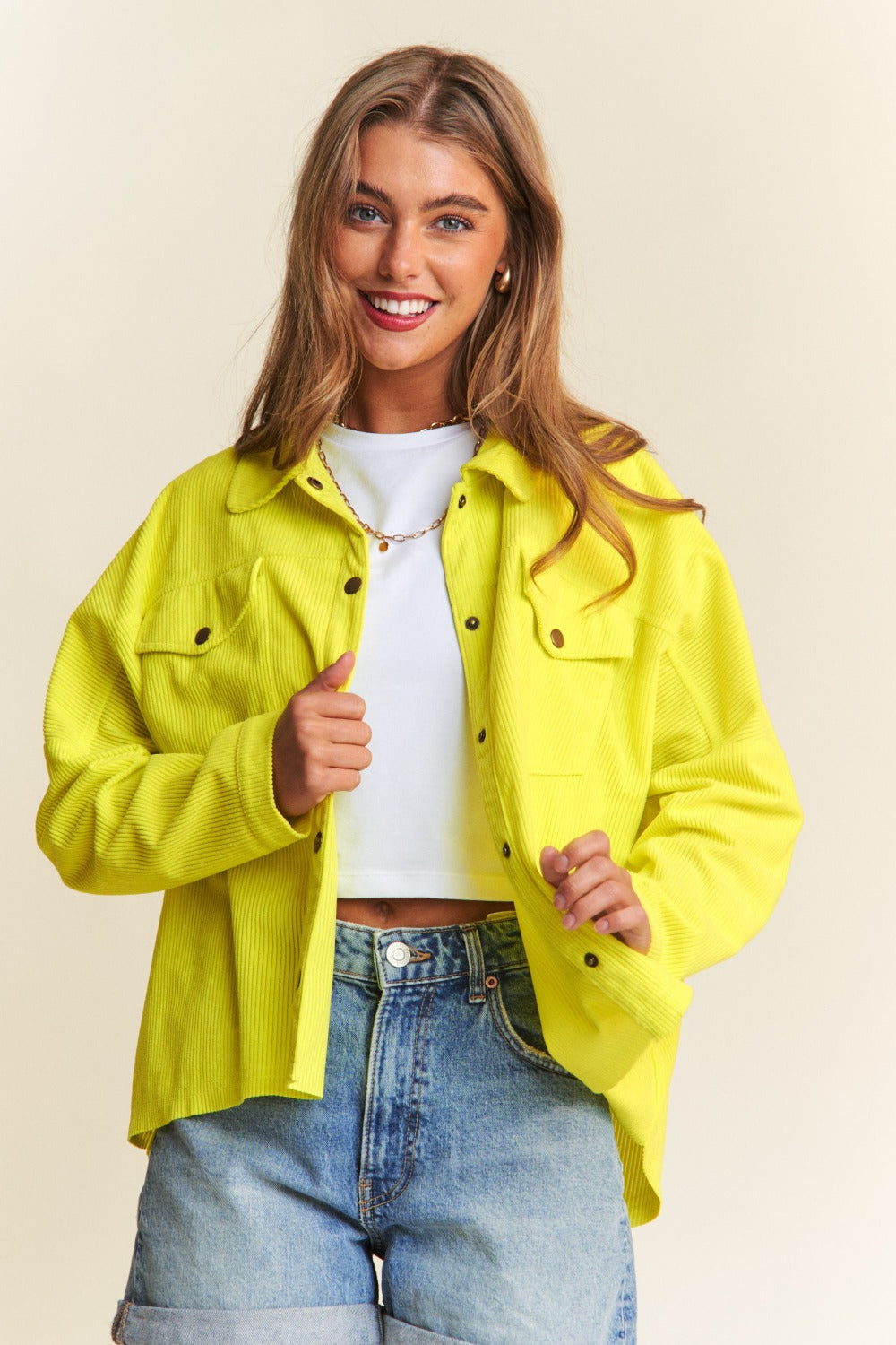 A chartreuse high-low shacket with long sleeves, a collared neckline, and snap-button closure. 