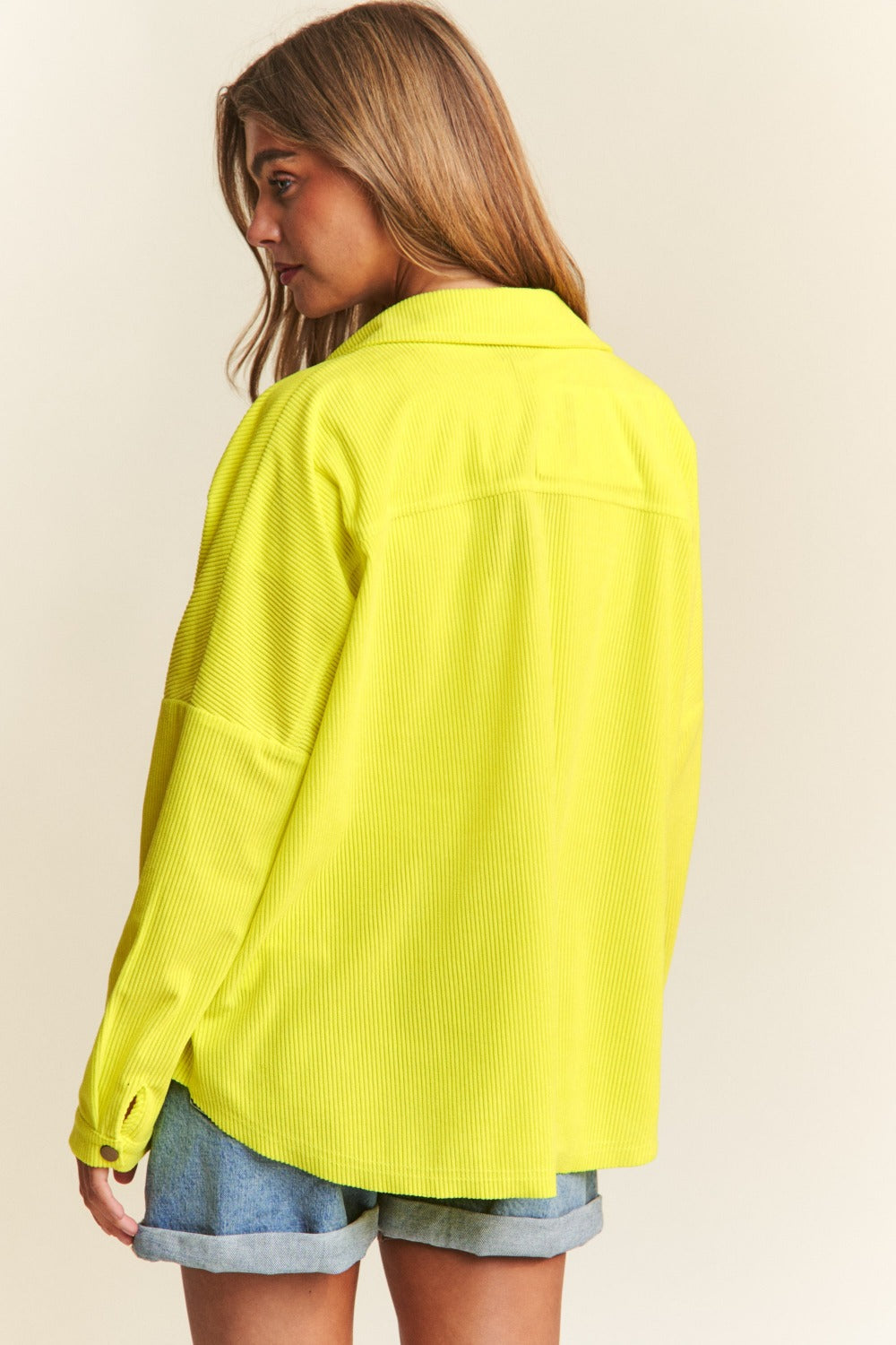 A chartreuse high-low shacket with long sleeves, a collared neckline, and snap-button closure. 