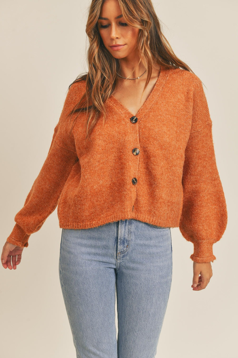 Women's rust colored cardigan with a V-neckline, long sleeves, button-down closure, and a relaxed fit.