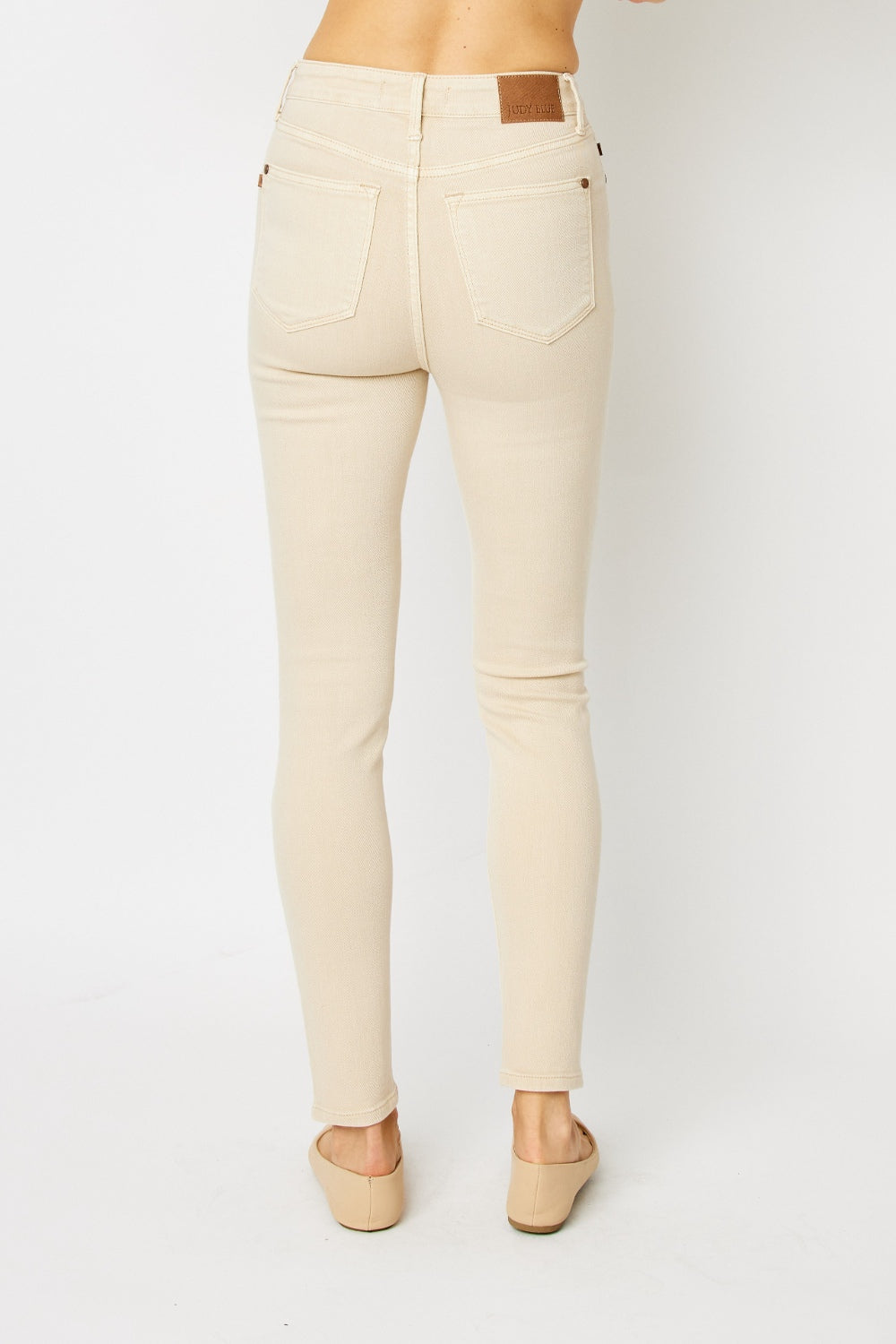 High-rise skinny jeans in bone with tummy control panel and zip fly. Slightly stretchy for comfort.