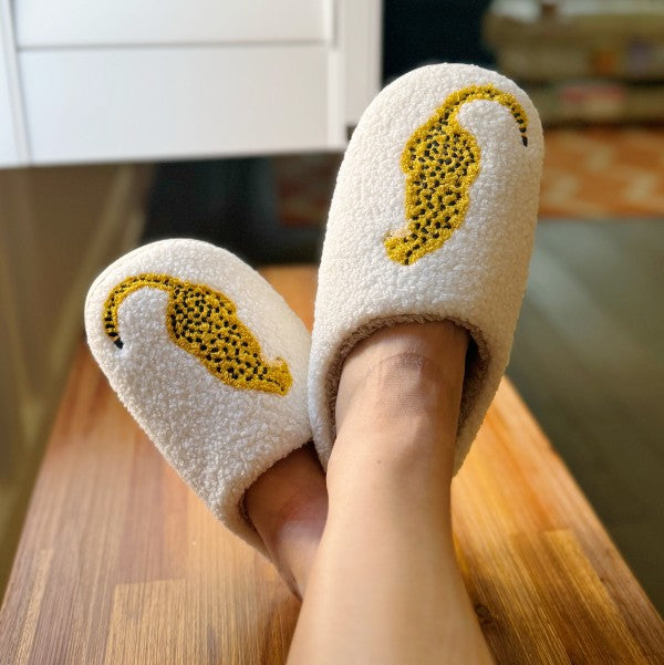 Woman wearing cozy cream sherpa cheetah slippers with embroidered design.