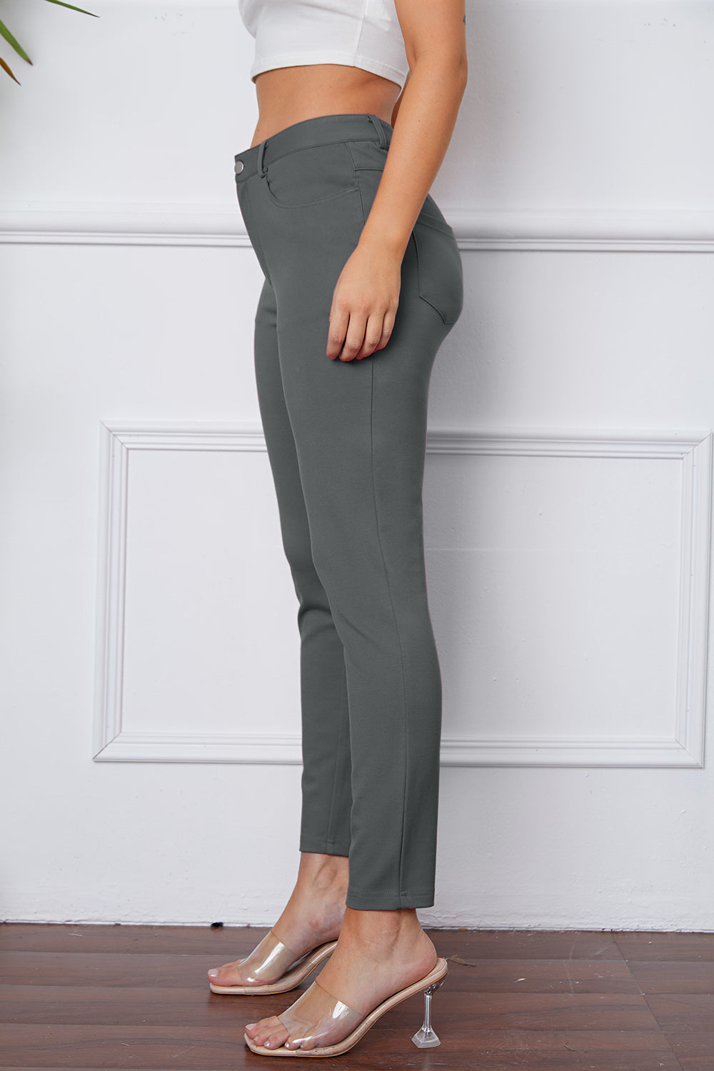 Gray stretchy high-waisted pants feature pockets, a zip fly, and belt loops. 