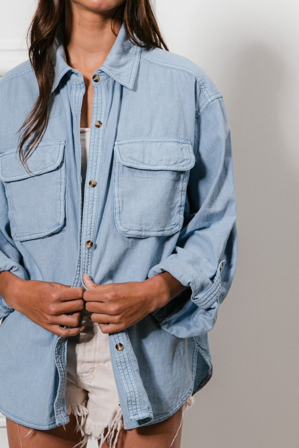 A denim button-down shirt with long sleeves, chest pockets, and detailed stitching. The shirt has a collared neckline and button closure.