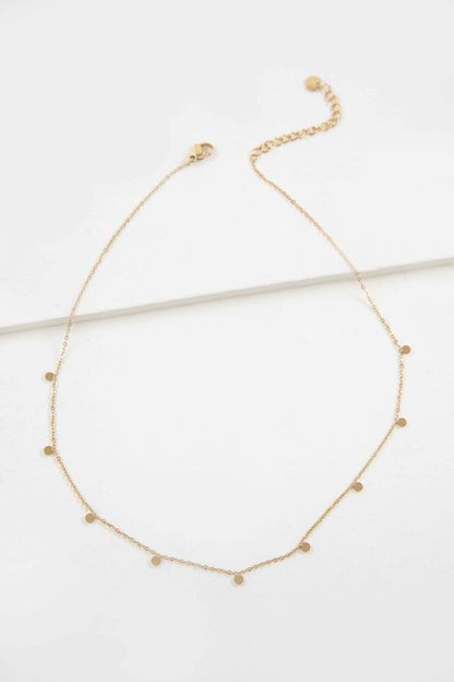 Flat lay of Golden Dot Charm Necklace with gold discs on fine chain
