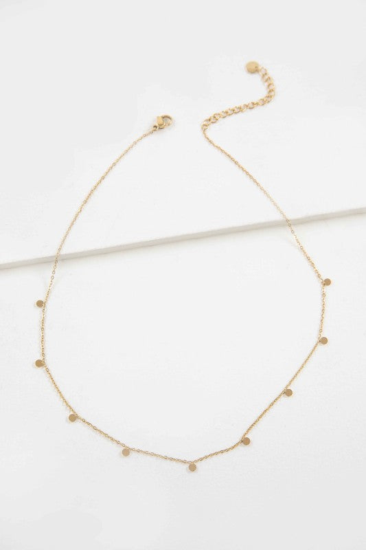 Flat lay of Golden Dot Charm Necklace with gold discs on fine chain