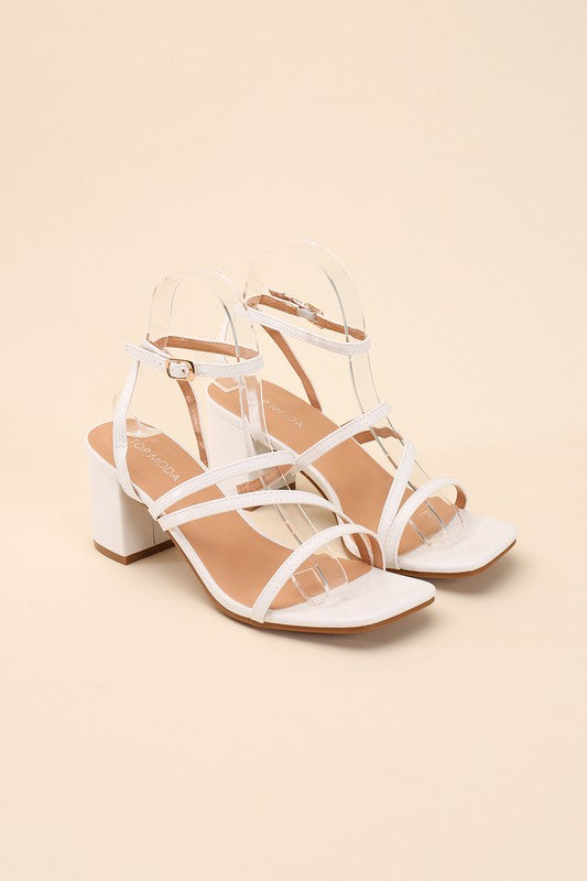 White strappy sandals with a 2" low heel, ankle strap closure, and criss-cross embellishments.