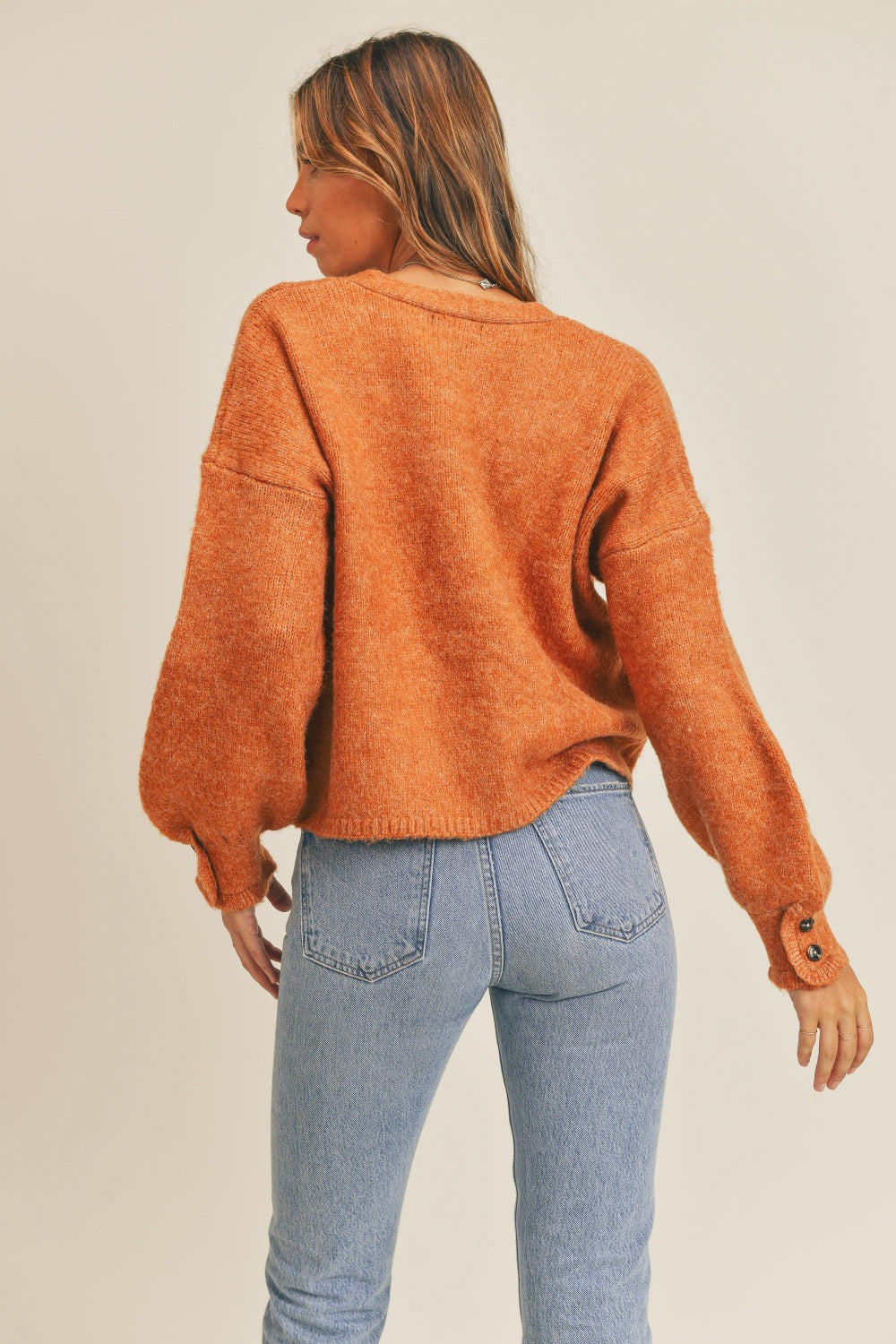 Women's rust colored cardigan with a V-neckline, long sleeves, button-down closure, and a relaxed fit.