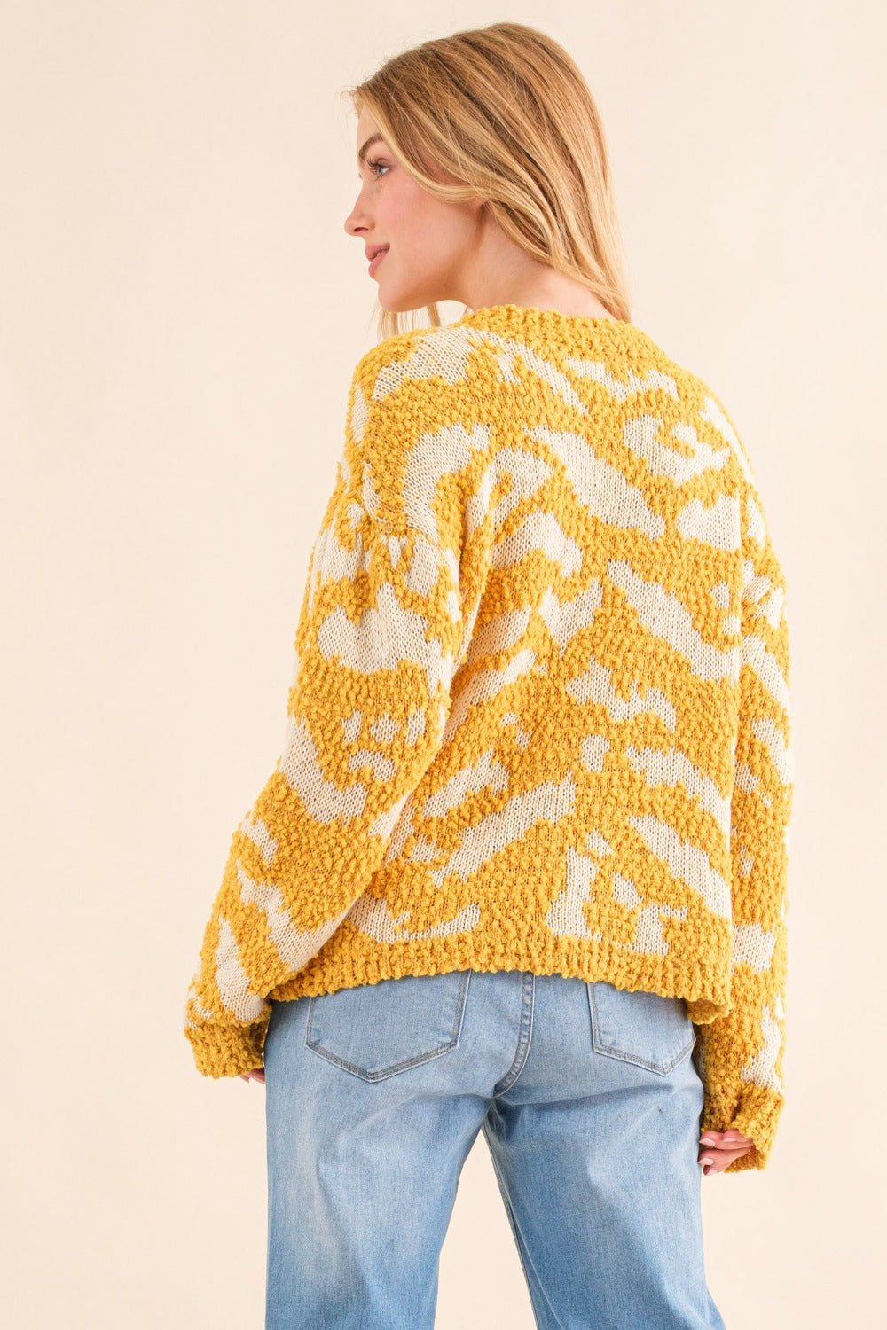 Women's textured mustard sweater with a round neckline and long sleeves.