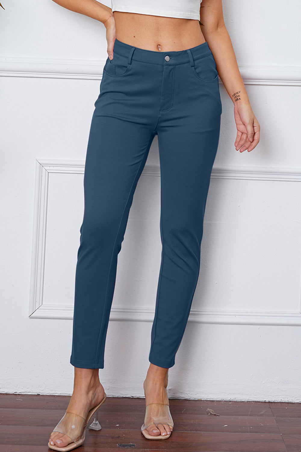 Dusty blue stretchy high-waisted pants feature pockets, a zip fly, and belt loops. 