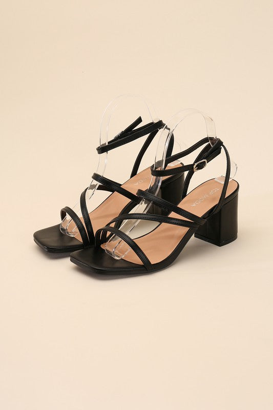 Black strappy sandals with a 2" low heel, ankle strap closure, and criss-cross embellishments.