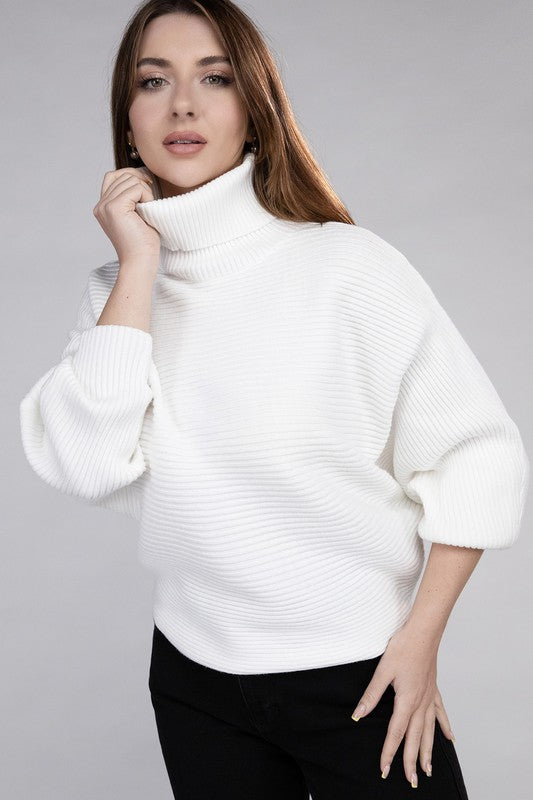 Off white loose fitting turtleneck sweater, with ribbed knit texture, dolman sleeves, and raw hem detailing.