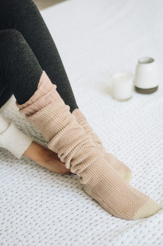 Woman sitting wearing pink Jerica Knitted Lounge Socks with large banded cuff.
