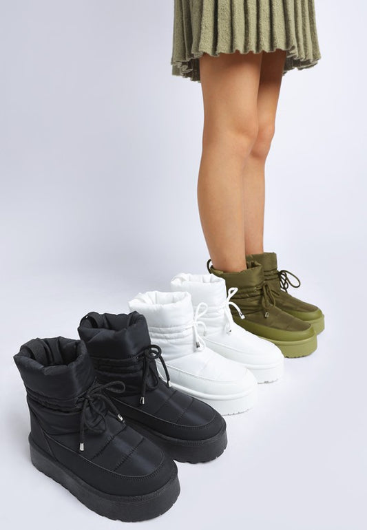 Model wearing khaki green Pacos Snow Boots with black and white pairs beside.
