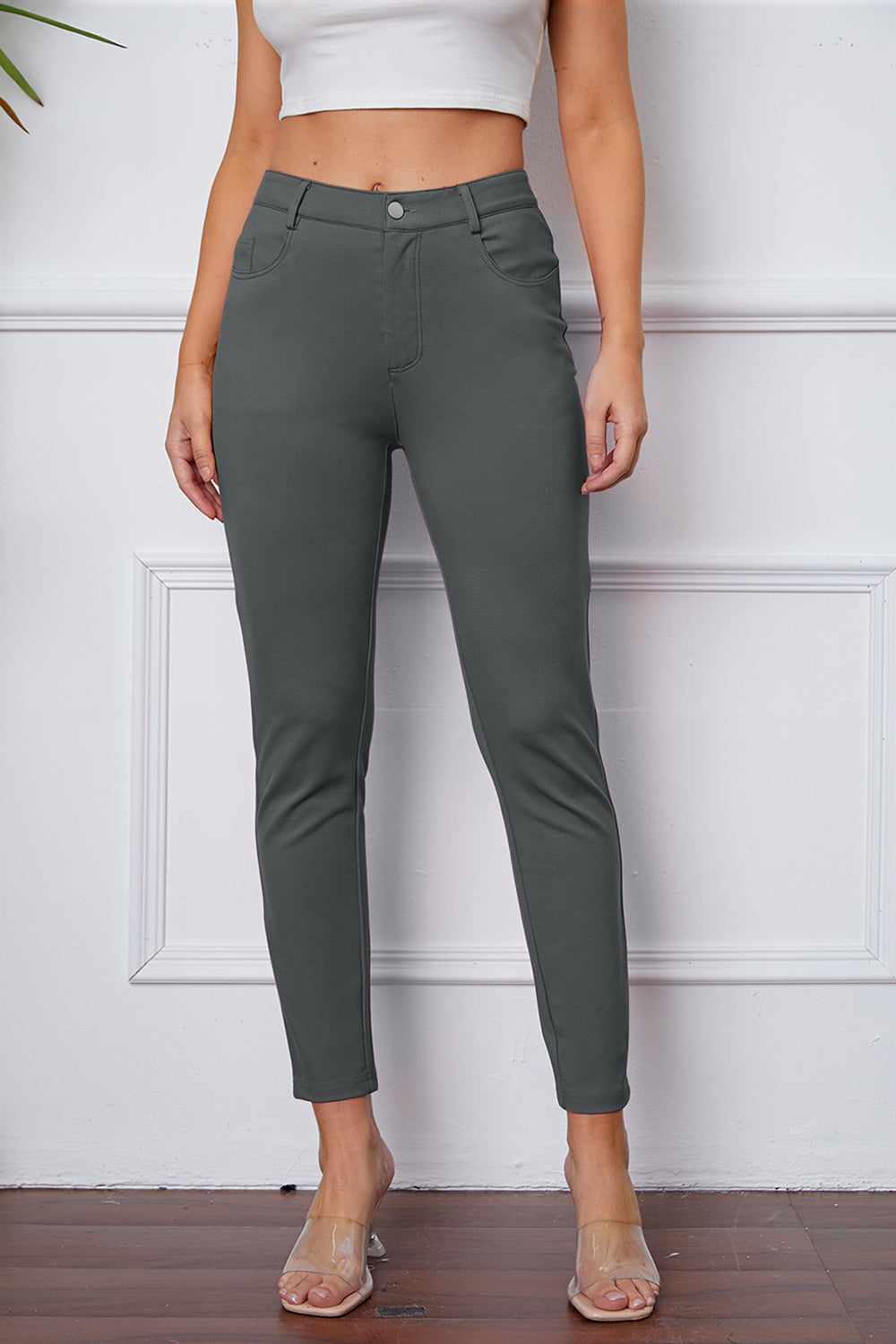 Gray stretchy high-waisted pants feature pockets, a zip fly, and belt loops. 