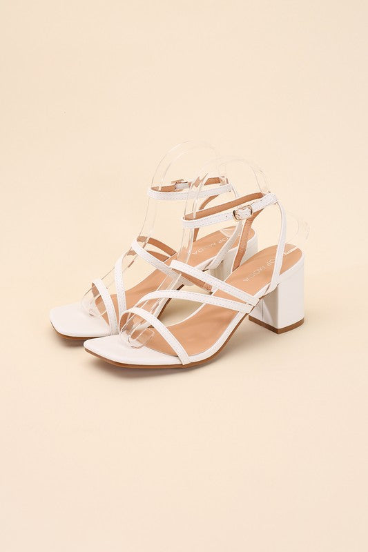 White strappy sandals with a 2" low heel, ankle strap closure, and criss-cross embellishments.