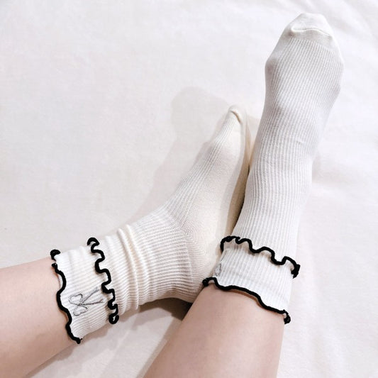 Woman wearing cream Ribbon Ripple Socks styled with ruffle trim and bow embroidery.