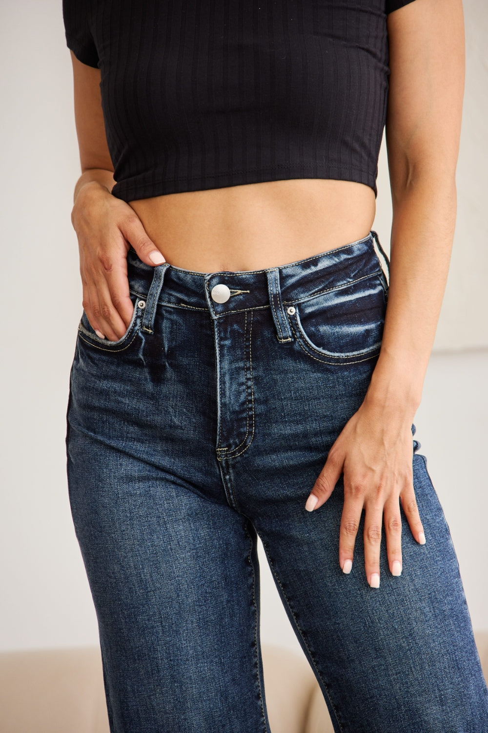 Dark wash high-waisted cropped jeans with tummy control, raw hem, and distressed details