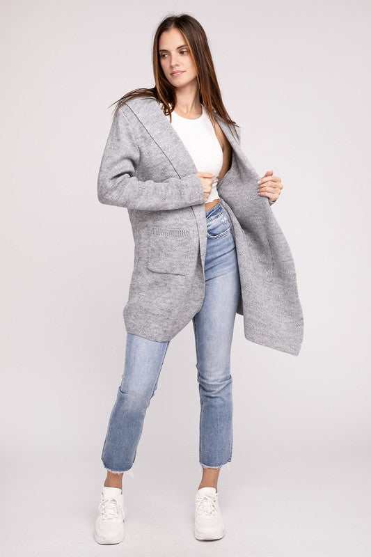 Grey sweater cardigan with long sleeves, front pockets, and a hooded neckline. 